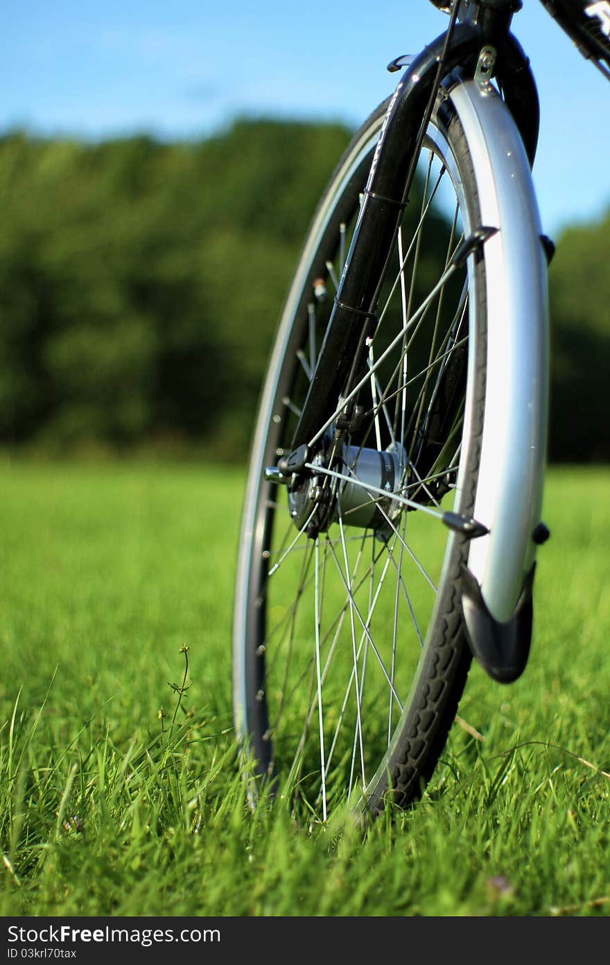 It shows a close up of a front wheel of a bike. It shows a close up of a front wheel of a bike