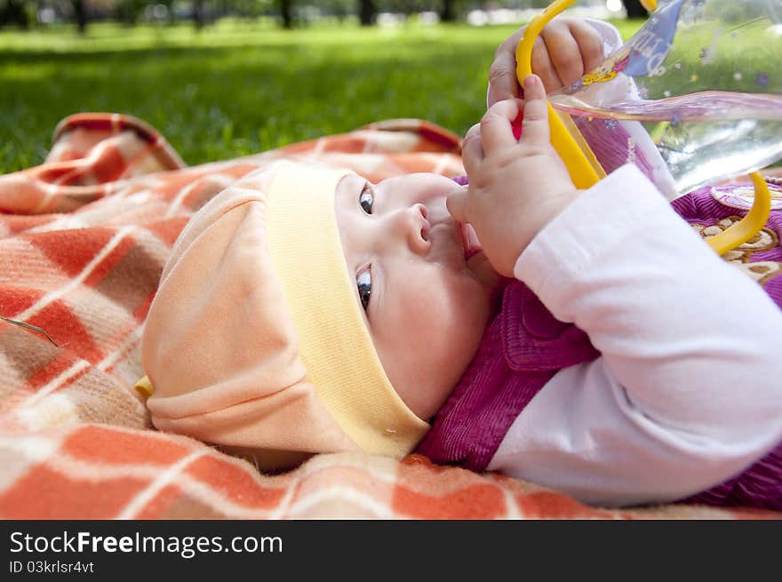 The portrait of the kid, lays on on a coverlet and drink water