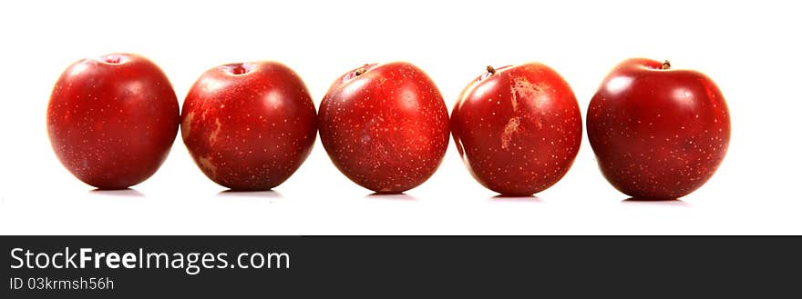 Ripe red plums over white background.