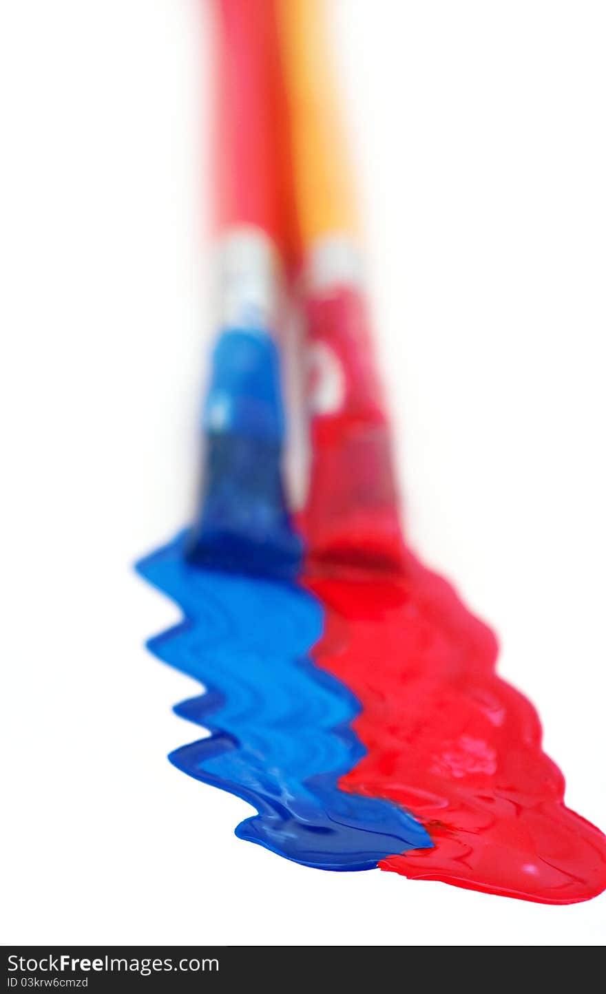 Two paintbrushes painting red and blue on white with shallow depth of field. Two paintbrushes painting red and blue on white with shallow depth of field