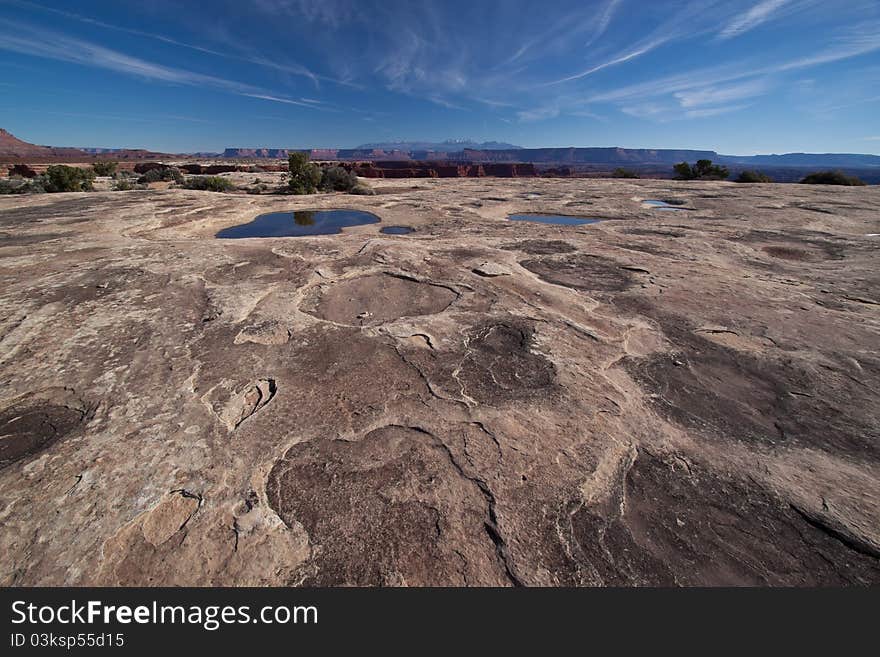 In the White Crack area of the White Rim Road in the Canyonlands National Park, the vistas are spectacular.  The La Sal Mountains can be seen again in the distance.  Filled water pockets can be seen, ans also evidence of airplanes flying haphazardly above, leaving their intriguing  design  of jet trails. In the White Crack area of the White Rim Road in the Canyonlands National Park, the vistas are spectacular.  The La Sal Mountains can be seen again in the distance.  Filled water pockets can be seen, ans also evidence of airplanes flying haphazardly above, leaving their intriguing  design  of jet trails.