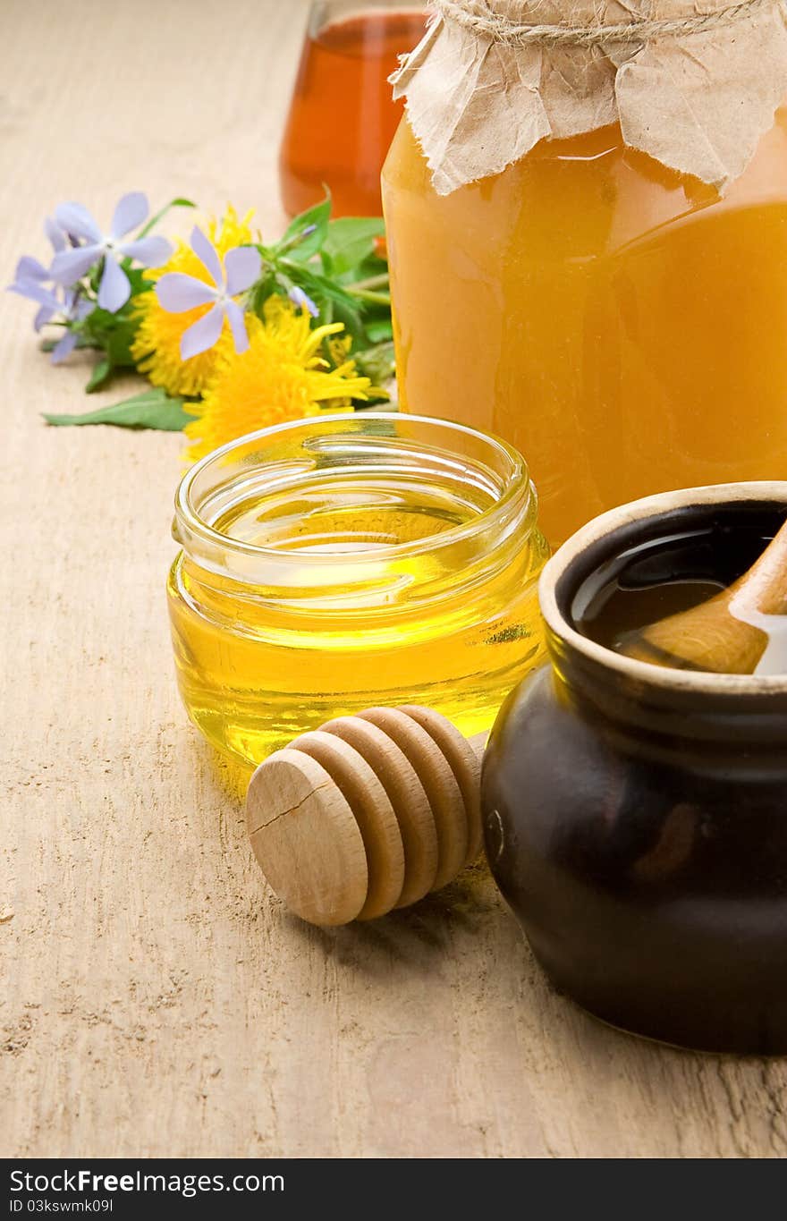 Honey in jars and flower on wood texture