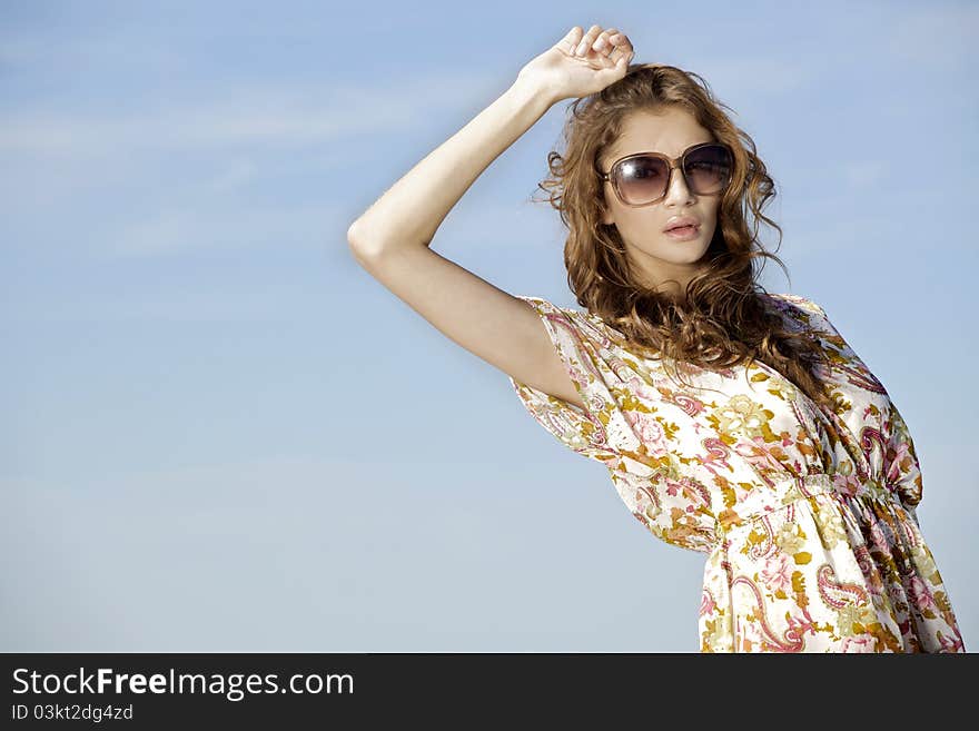 Portrait of beautiful brunette girl in sunglasses on background blue sky. Portrait of beautiful brunette girl in sunglasses on background blue sky