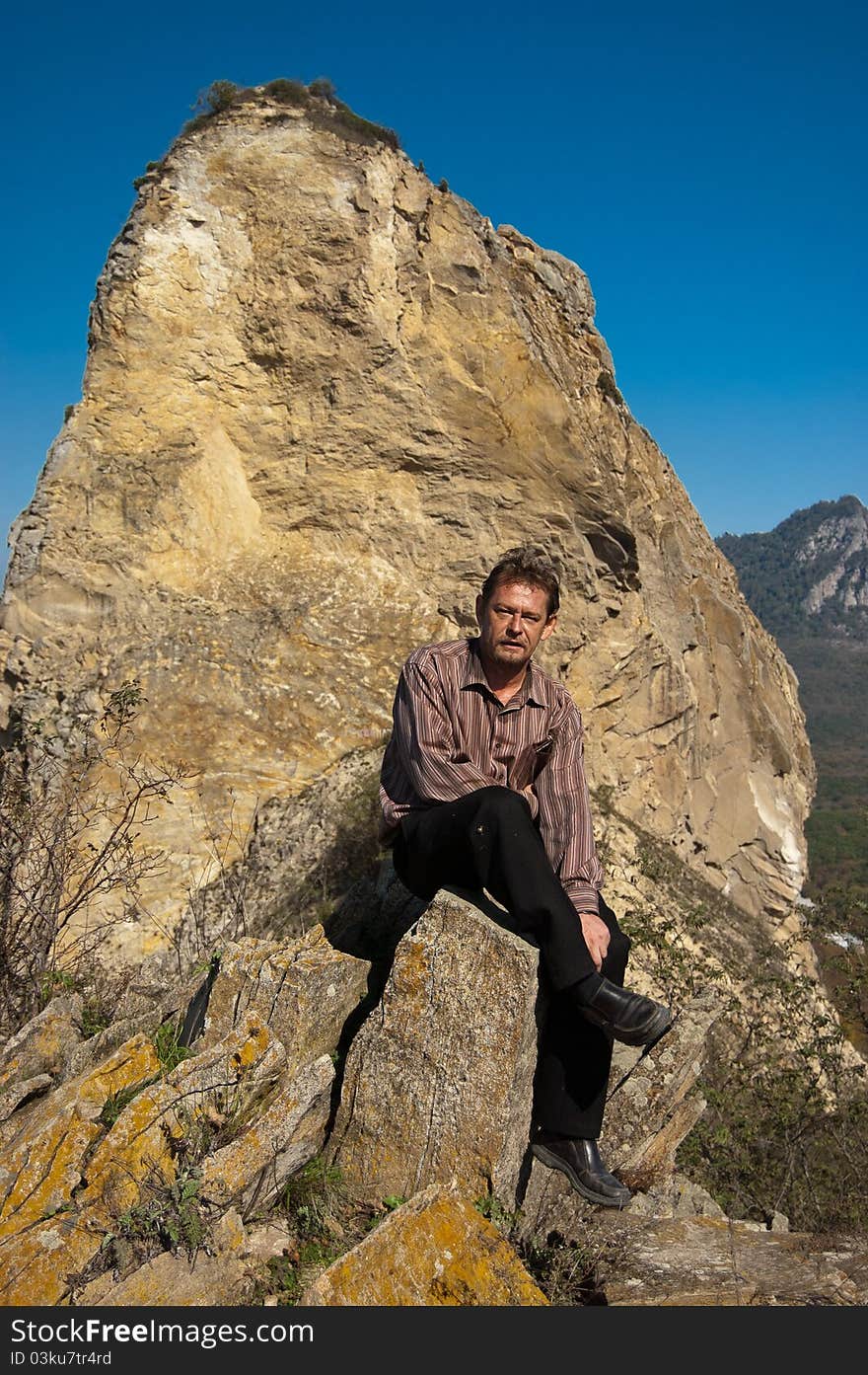 Man sitting on a rock in the mountains. Man sitting on a rock in the mountains