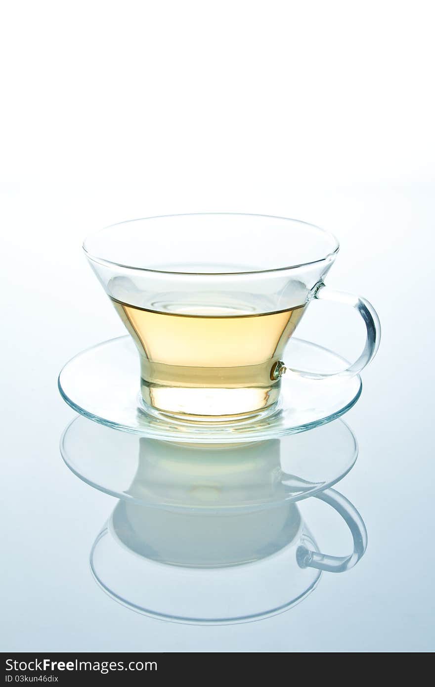 Isolated glass cup of tea or another liquid with reflection standing on a glass table