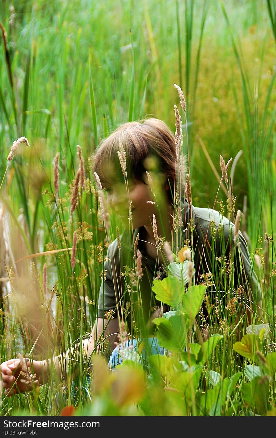 Boy hiding behind grass and leaves in a field. Boy hiding behind grass and leaves in a field.