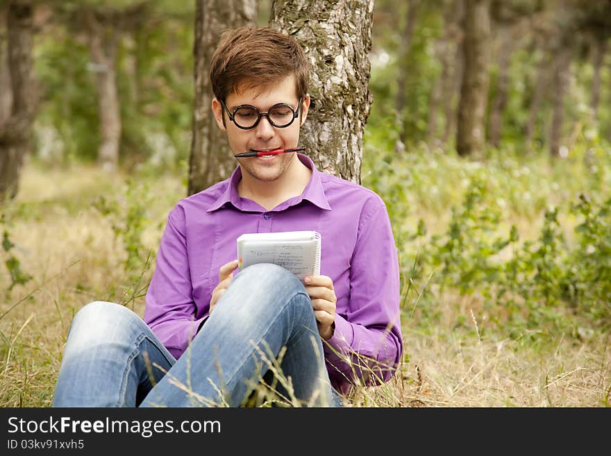 Funny men with glasses doing homework at the park.