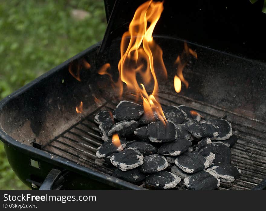 Charcoal has caught fire and is turning from black and cold to white hot and ready for cooking. Charcoal has caught fire and is turning from black and cold to white hot and ready for cooking.