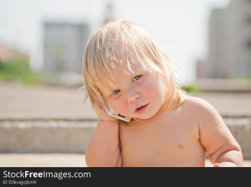 Adorable baby play with cell phone calling sitting on stairs on walk road