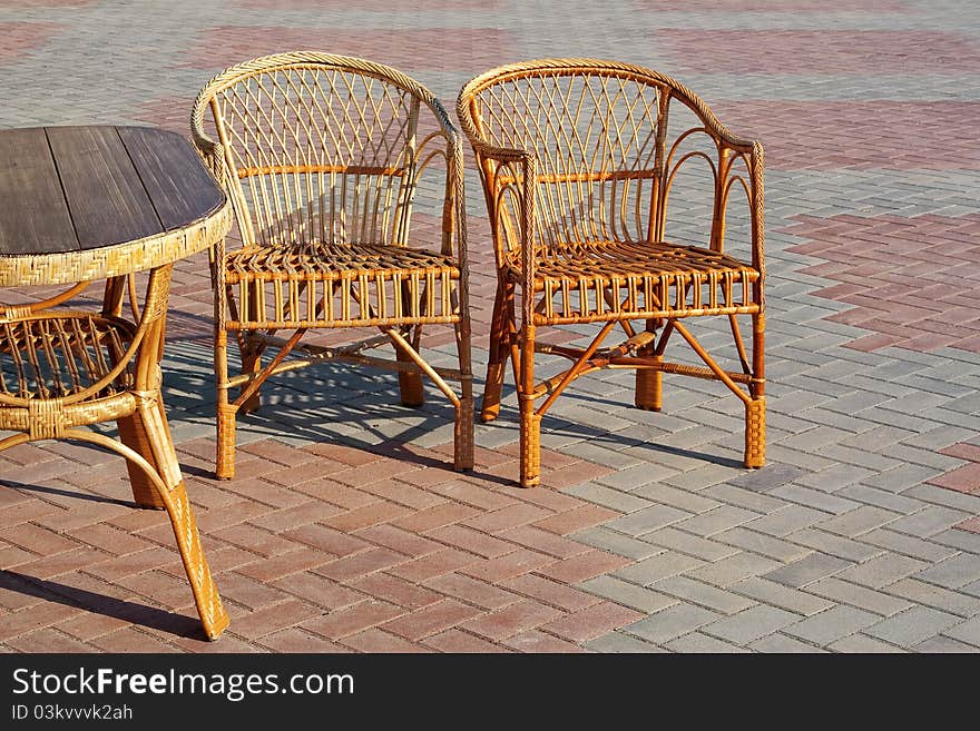 Two wicker chairs and a table in a summer cafe. Two wicker chairs and a table in a summer cafe