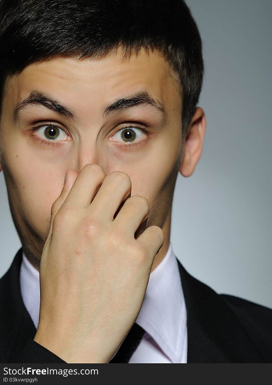 Expressions Young handsome business man touching his nose . studio shot