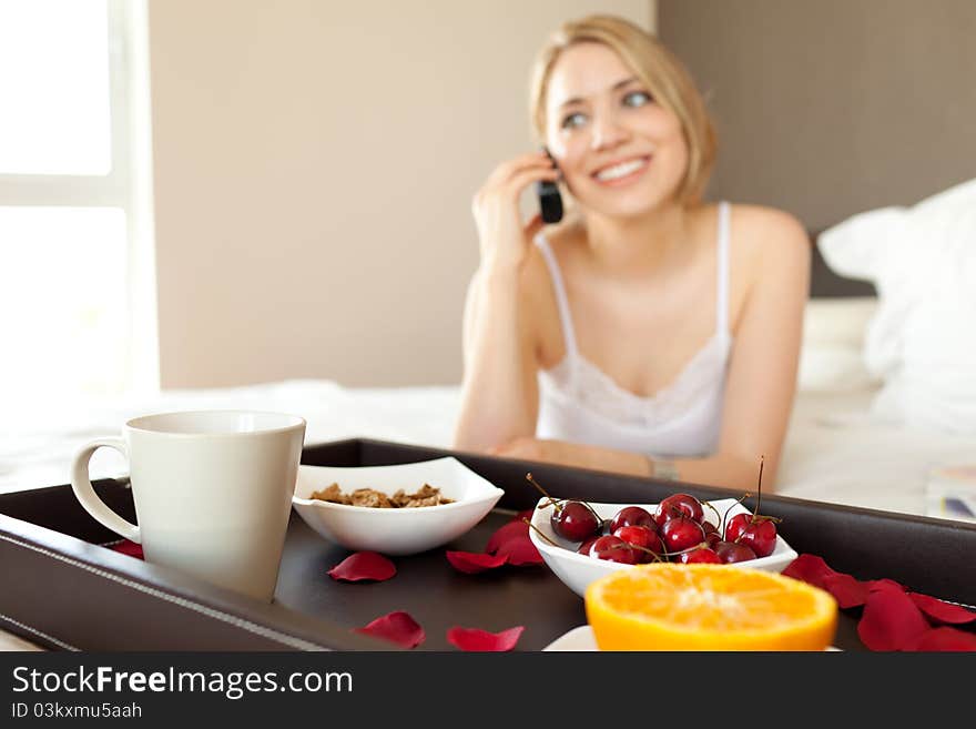 Happy woman having healthy breakfast at the bed when talking by phone. Happy woman having healthy breakfast at the bed when talking by phone