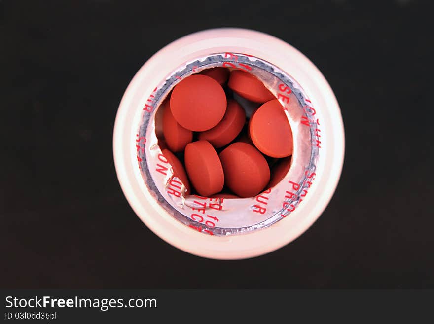 Small bottle of pills over black background