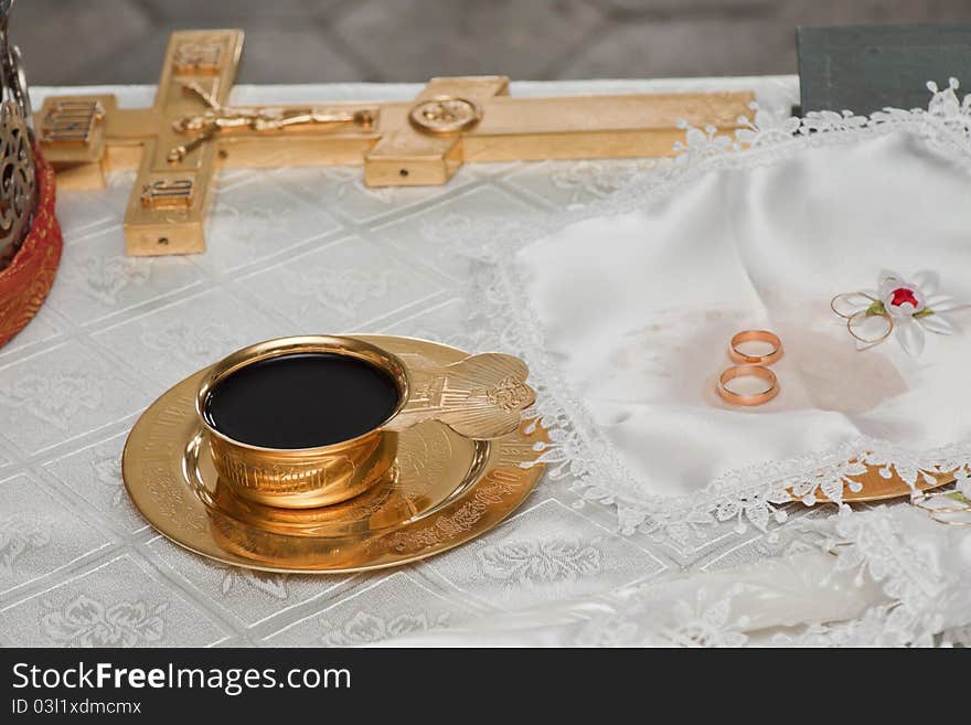 Wedding rings lay on a table near a bowl with wine. Wedding rings lay on a table near a bowl with wine