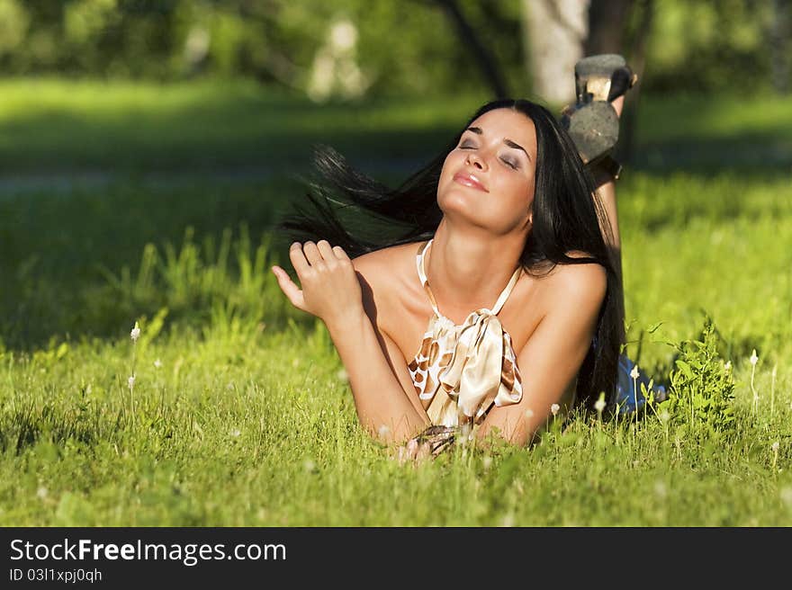 Young beautiful brunette lying on the grass on a summer day