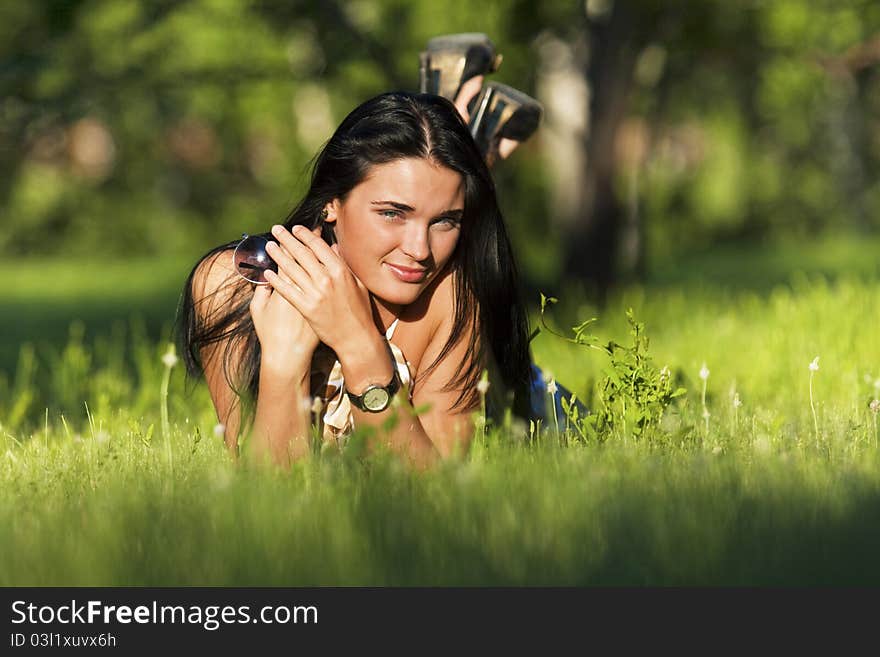 Young beautiful brunette lying on the grass on a summer day