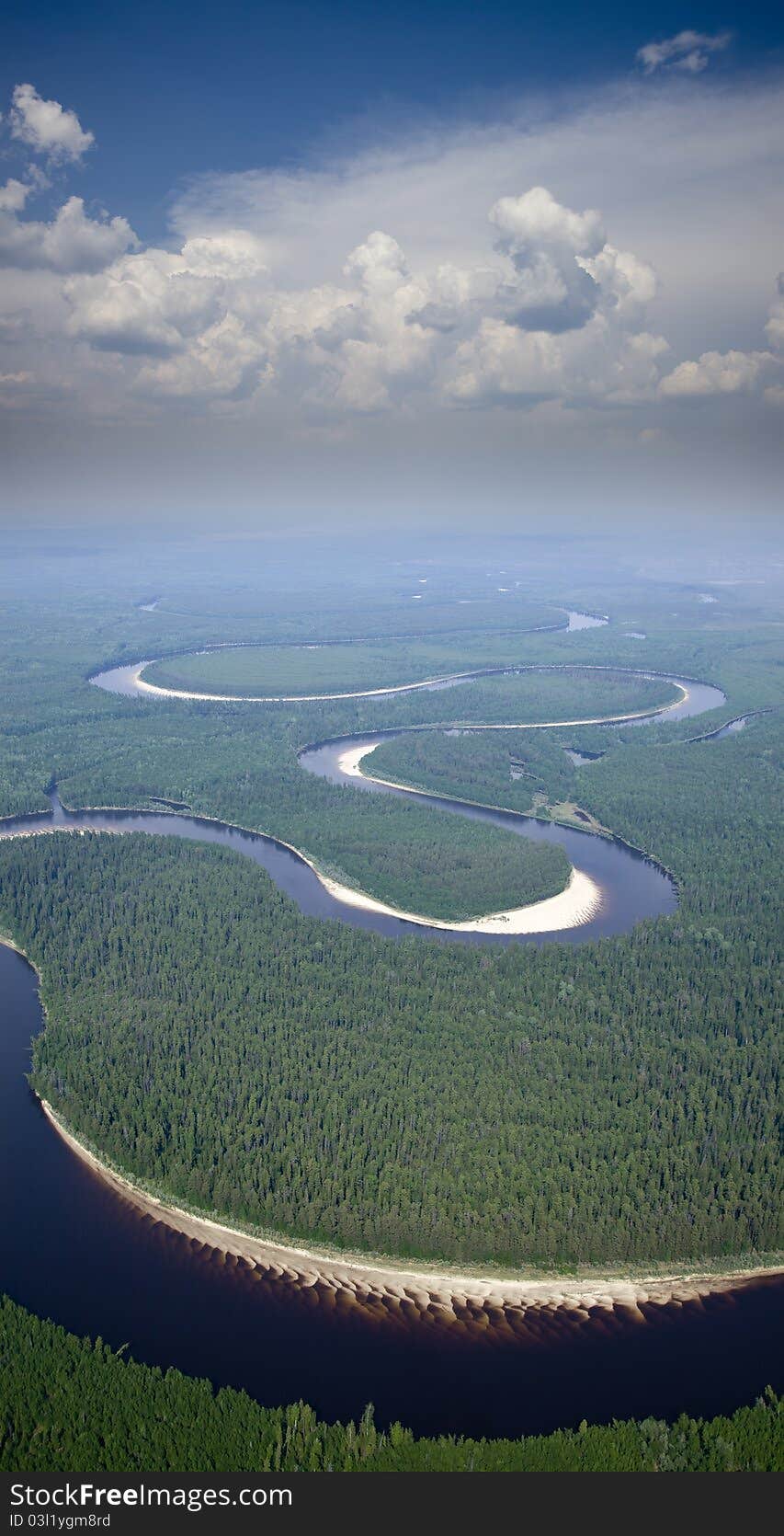 Aerial view of the river which doing loops in the woods under the white clouds. Aerial view of the river which doing loops in the woods under the white clouds.