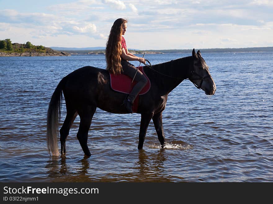 The girl has a horse to water in the evening at sunset. The girl has a horse to water in the evening at sunset