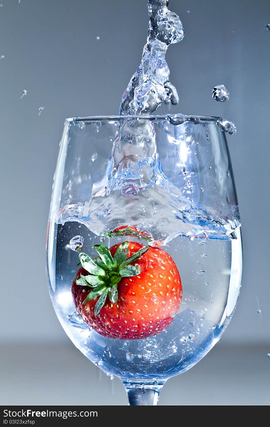 A strawberry submerged in a glass of liquid. A strawberry submerged in a glass of liquid.