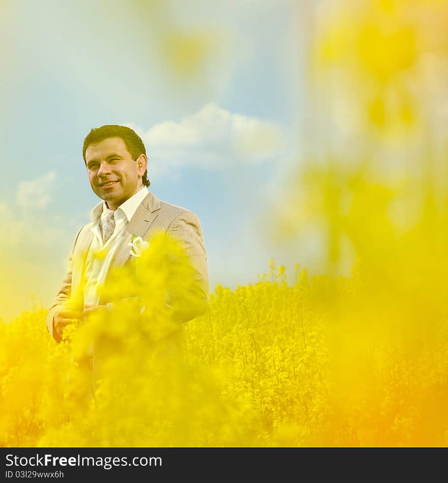 Man groom portrait in blossom sunny summer landscape with field of rape. Man groom portrait in blossom sunny summer landscape with field of rape