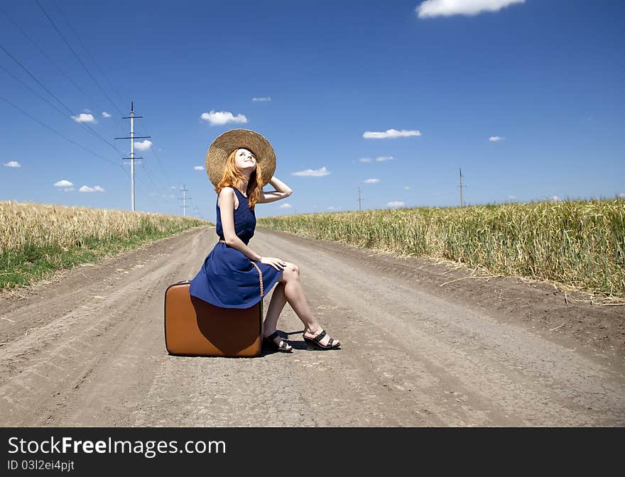 Lonely girl with suitcase at country road.