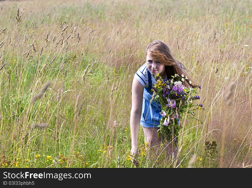 The red girl in the field collects a bunch of flowers