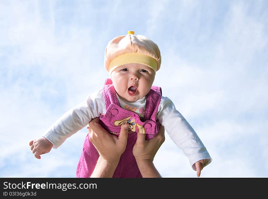 Father playing with baby, raised it high above them, against the background of blue sky. Father playing with baby, raised it high above them, against the background of blue sky