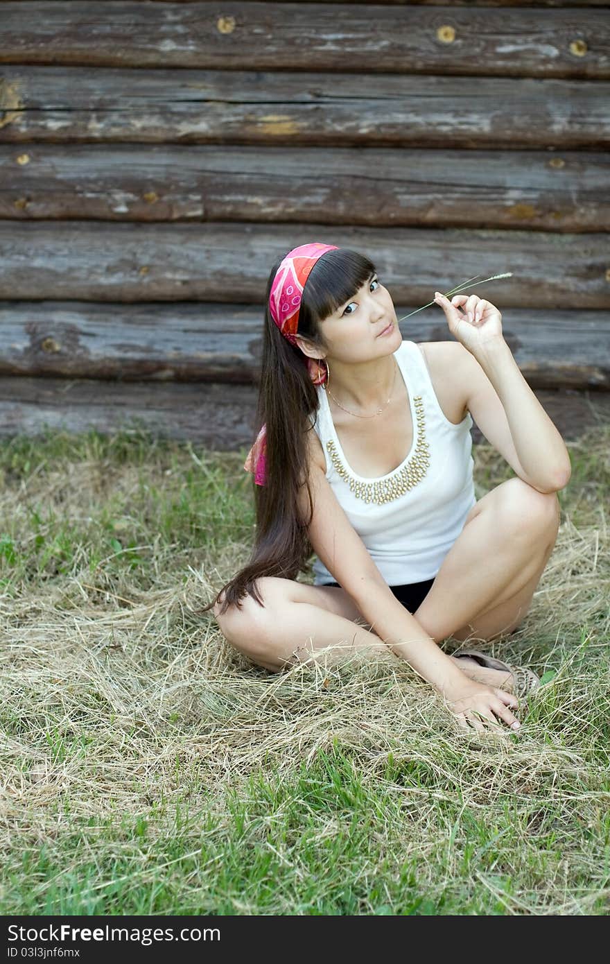 Beautiful girl sitting on hay in country