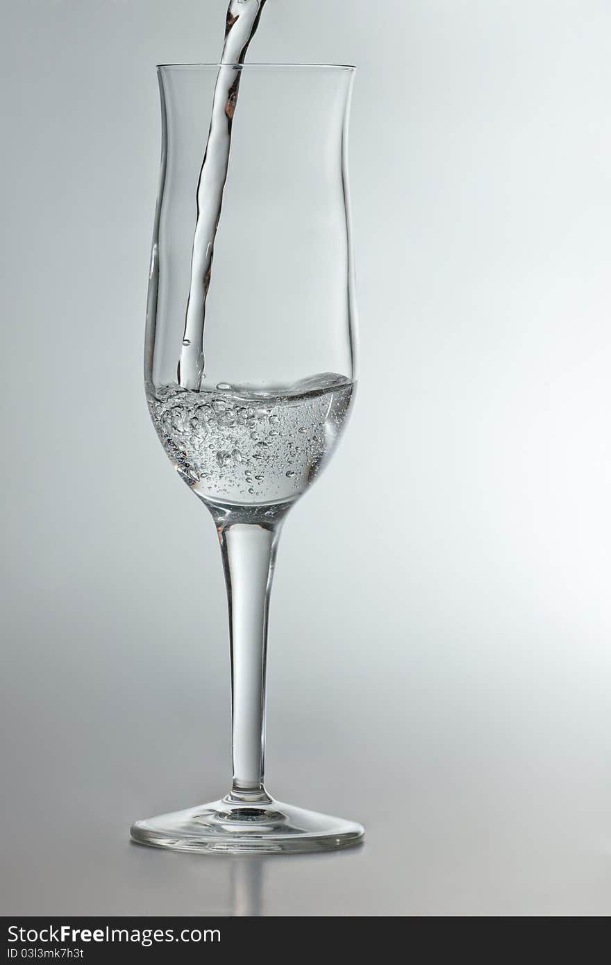 Pouring sparkling water in champagne glass isolated in white background. Pouring sparkling water in champagne glass isolated in white background