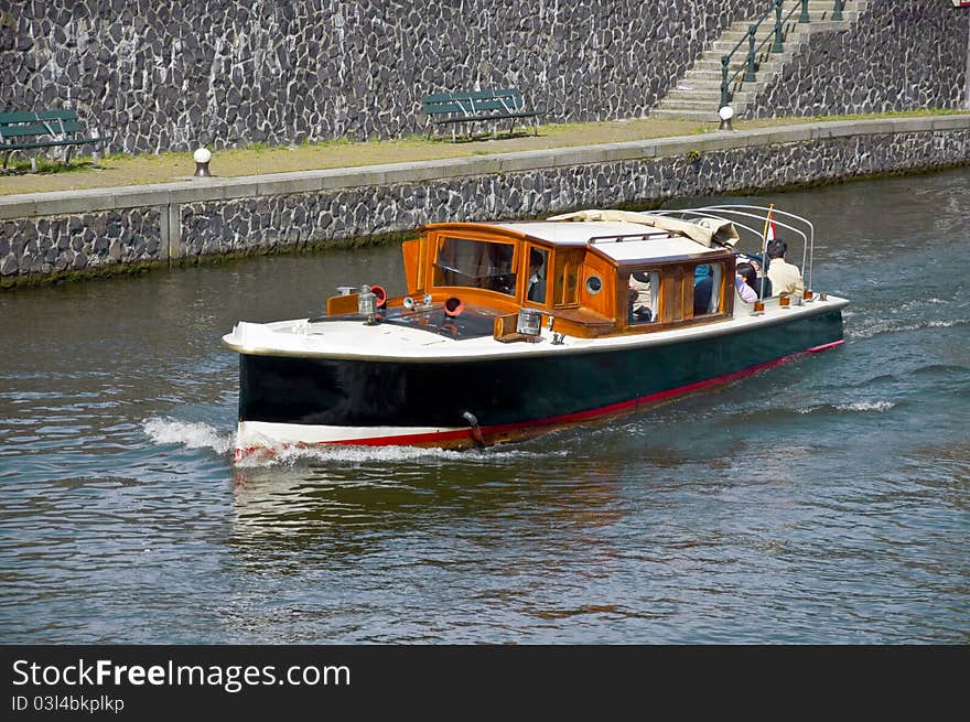 Passenger boat sails on the water channel along the stone quay.