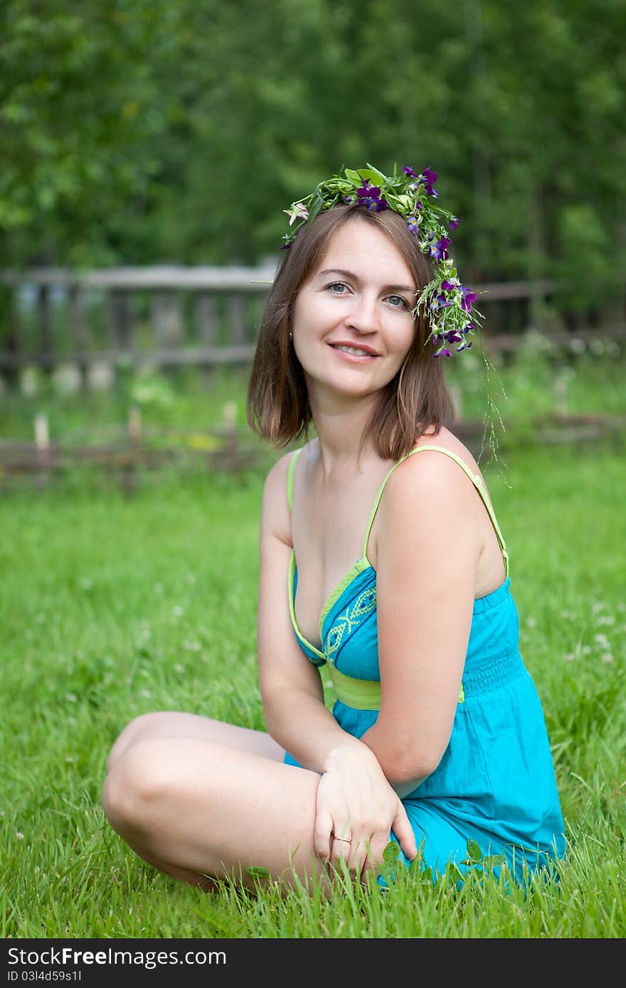 Young women with fower diadem sit on grass. Young women with fower diadem sit on grass