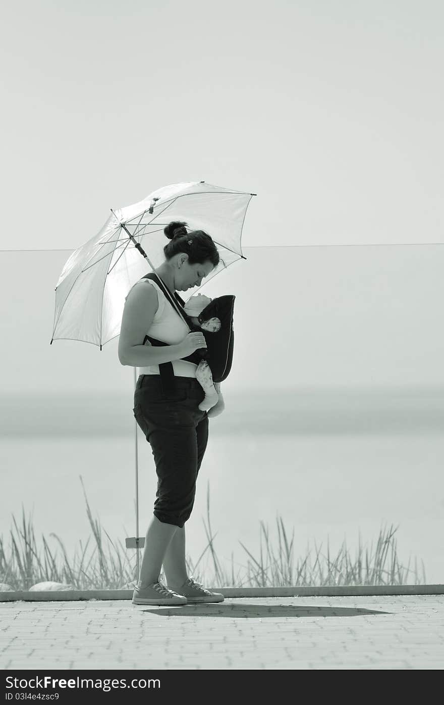 Mother holding her baby in career at seaside; black and white picture. Mother holding her baby in career at seaside; black and white picture