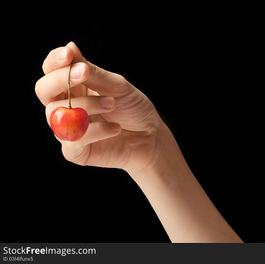 It is red a yellow sweet cherry lies on a hand of the young girl. It is red a yellow sweet cherry lies on a hand of the young girl