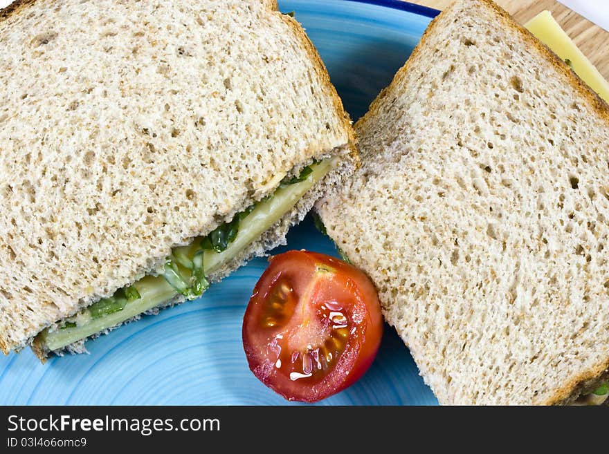 A close up of a sliced cheese and rocket salad with half a tomato on a blue plate. A close up of a sliced cheese and rocket salad with half a tomato on a blue plate