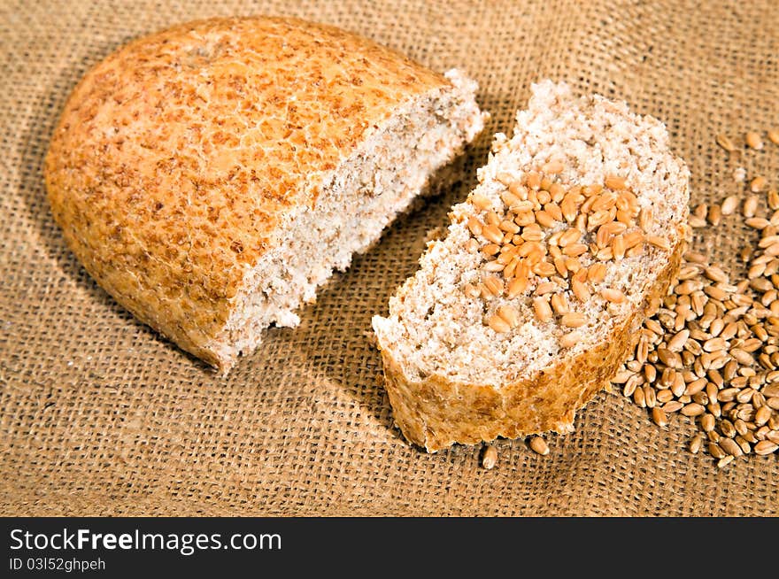 The loaf of bread lying together with wheat on a linen cloth. The loaf of bread lying together with wheat on a linen cloth