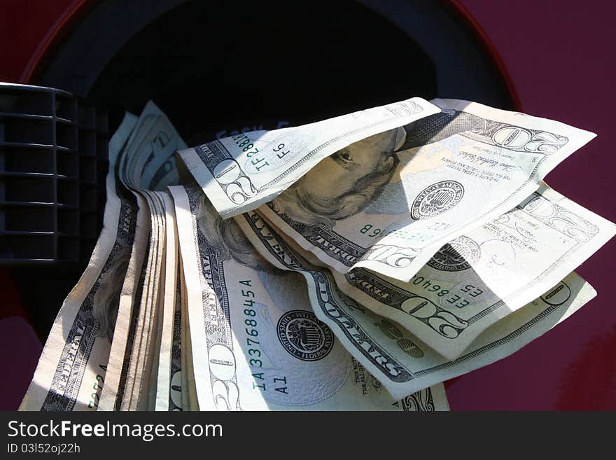 Money coming out of a gas tank in a red car. Money coming out of a gas tank in a red car.