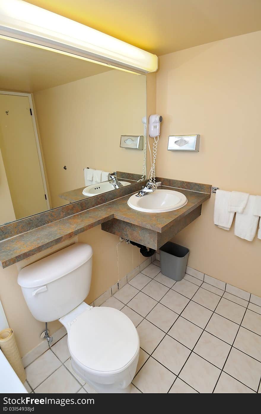 Typical hotel toilet area with toilet bowl, mirror and basin.