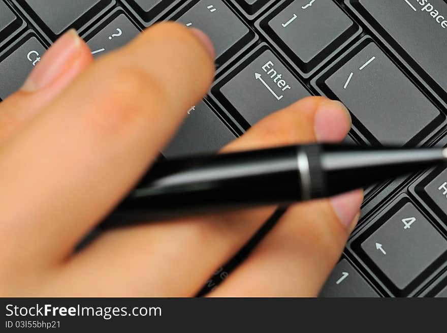 Macro of fingers typing while holding black pen. Macro of fingers typing while holding black pen.