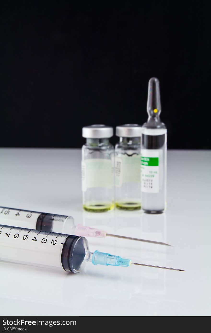 Syringe and small bottle of drug on the white table. Syringe and small bottle of drug on the white table