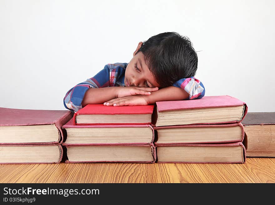 A small kid sleeping over fat books. A small kid sleeping over fat books