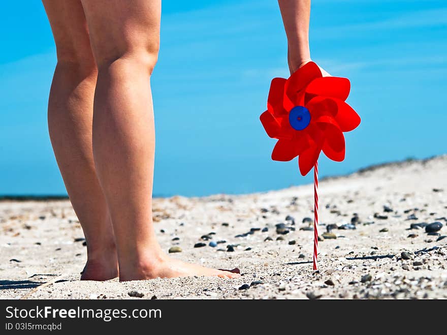 A red wind turbine on the sandy beach with two legs. A red wind turbine on the sandy beach with two legs