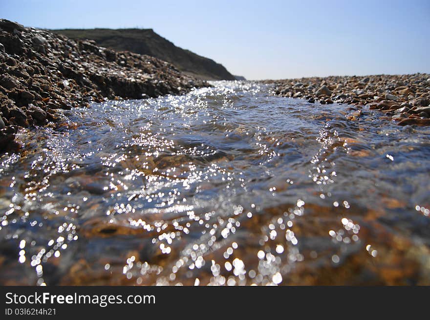 Fresh water stream on a bebble beach leading down to the ocean