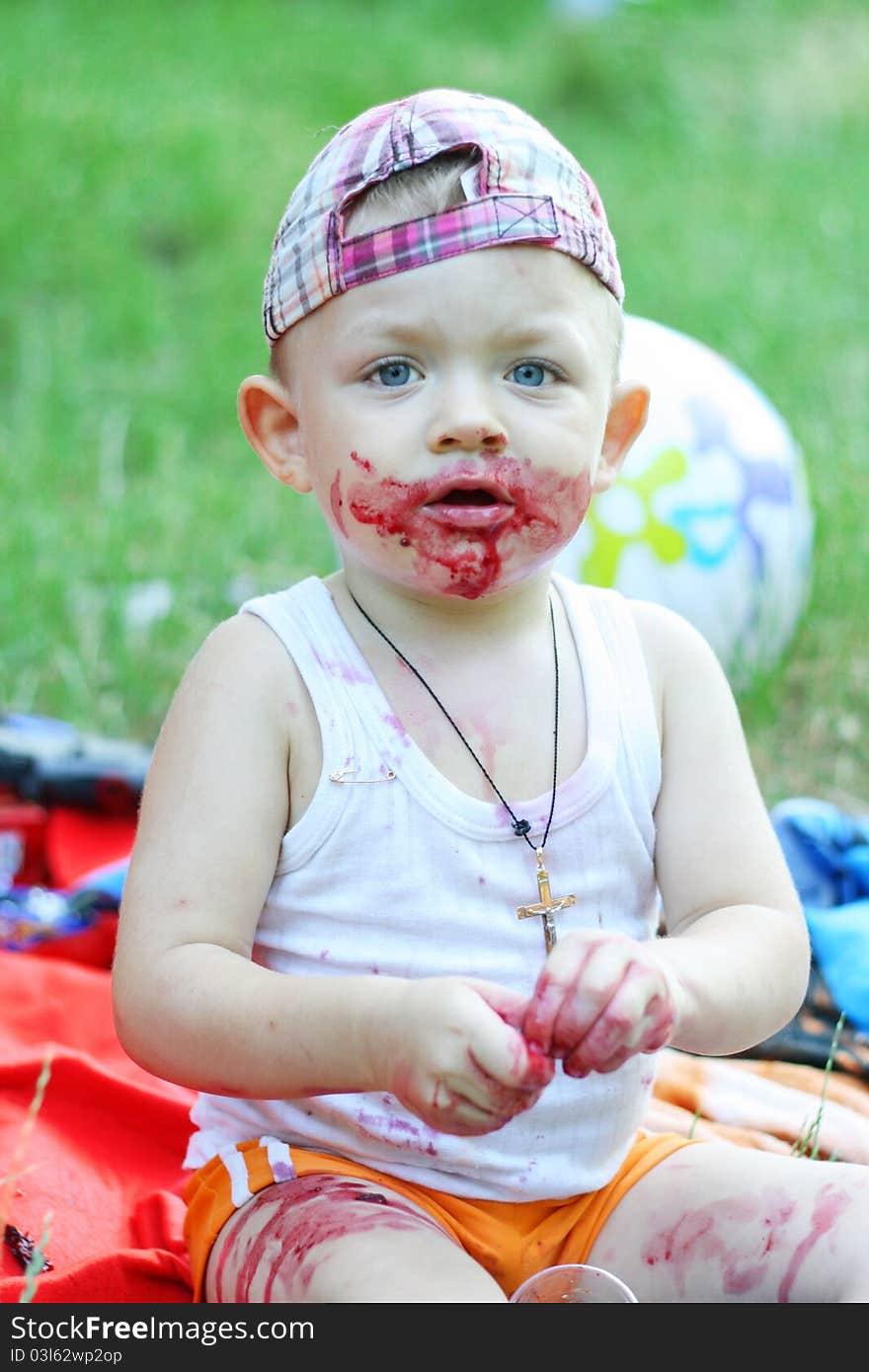 Baby boy in the meadow eating berries