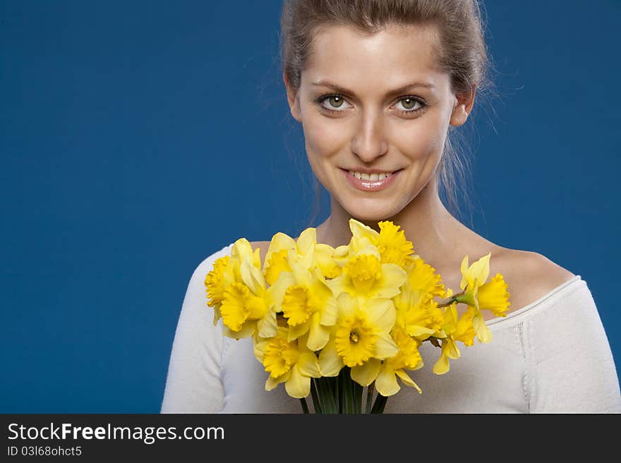 Young female with bunch of flowers on blue background. Young female with bunch of flowers on blue background