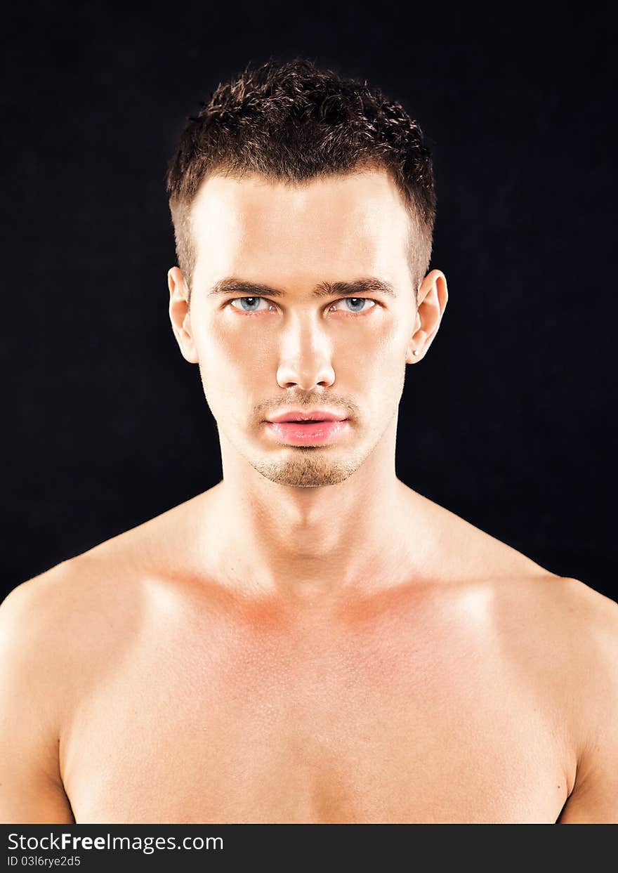 Portrait of a handsome young man with blue eyes on a black background