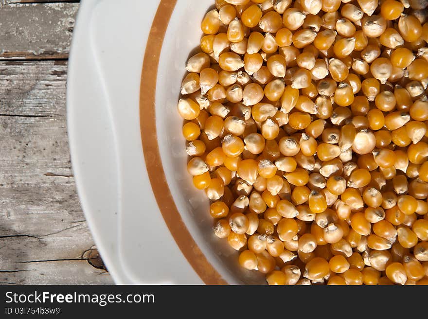 Whole corn on a plate on wooden table. Whole corn on a plate on wooden table