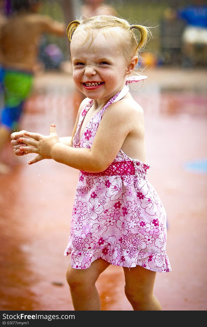 A young girl plays in the sprinklers at a waterpark. A young girl plays in the sprinklers at a waterpark