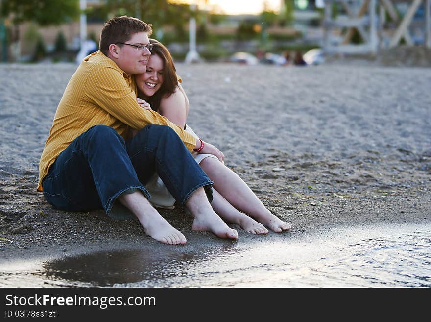 A young couple embrace each other by the water. A young couple embrace each other by the water