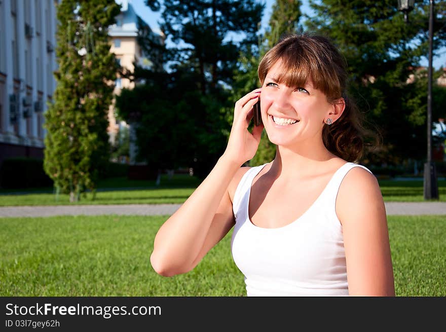 Portrait of young woman talking on phone, green grass background. Portrait of young woman talking on phone, green grass background