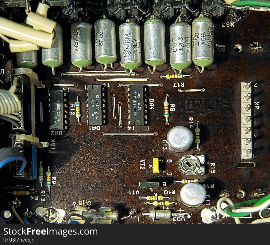 Old and dark microcircuit board with transistors, capacitors, chips and other elements